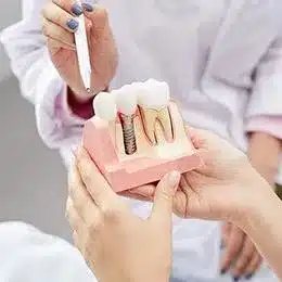 Dentist presenting dental implant model to patient during consultation at dental office.
