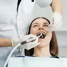 Woman receiving dental examination from dentist using professional tools in clinical setting.
