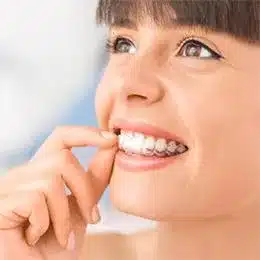Child smiling while flossing teeth against blurred blue background, demonstrating dental hygiene care.